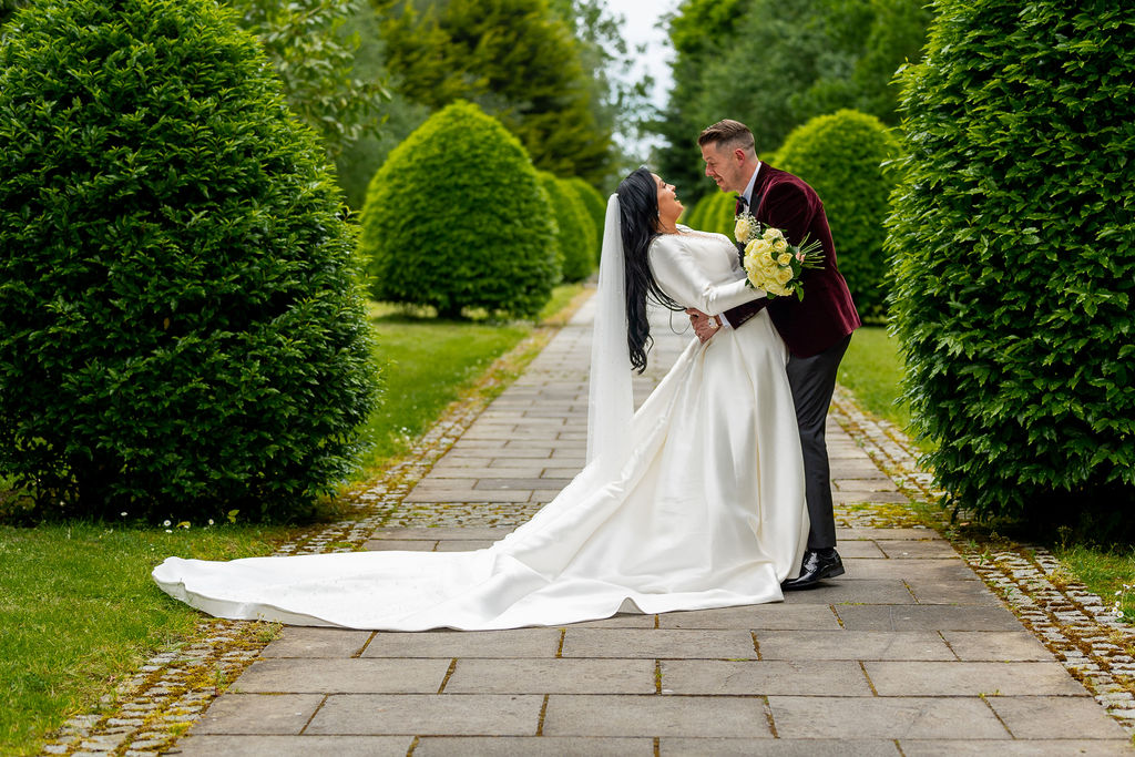 Elegant Irish Garden Wedding Photography at Exclusive Wedding Venue in Ireland— Silverscreen.ie (© All Rights Reserved Dougie Farrelly Silverscreen.ie) Groom dips smiling bride in a white wedding dress holding bouquet, surrounded by lush green trees on a garden path in an exclusive wedding venue in Ireland — wedding photography by Dougie Farrelly, Silverscreen.ie. (© All Rights Reserved Dougie Farrelly Silverscreen.ie)
