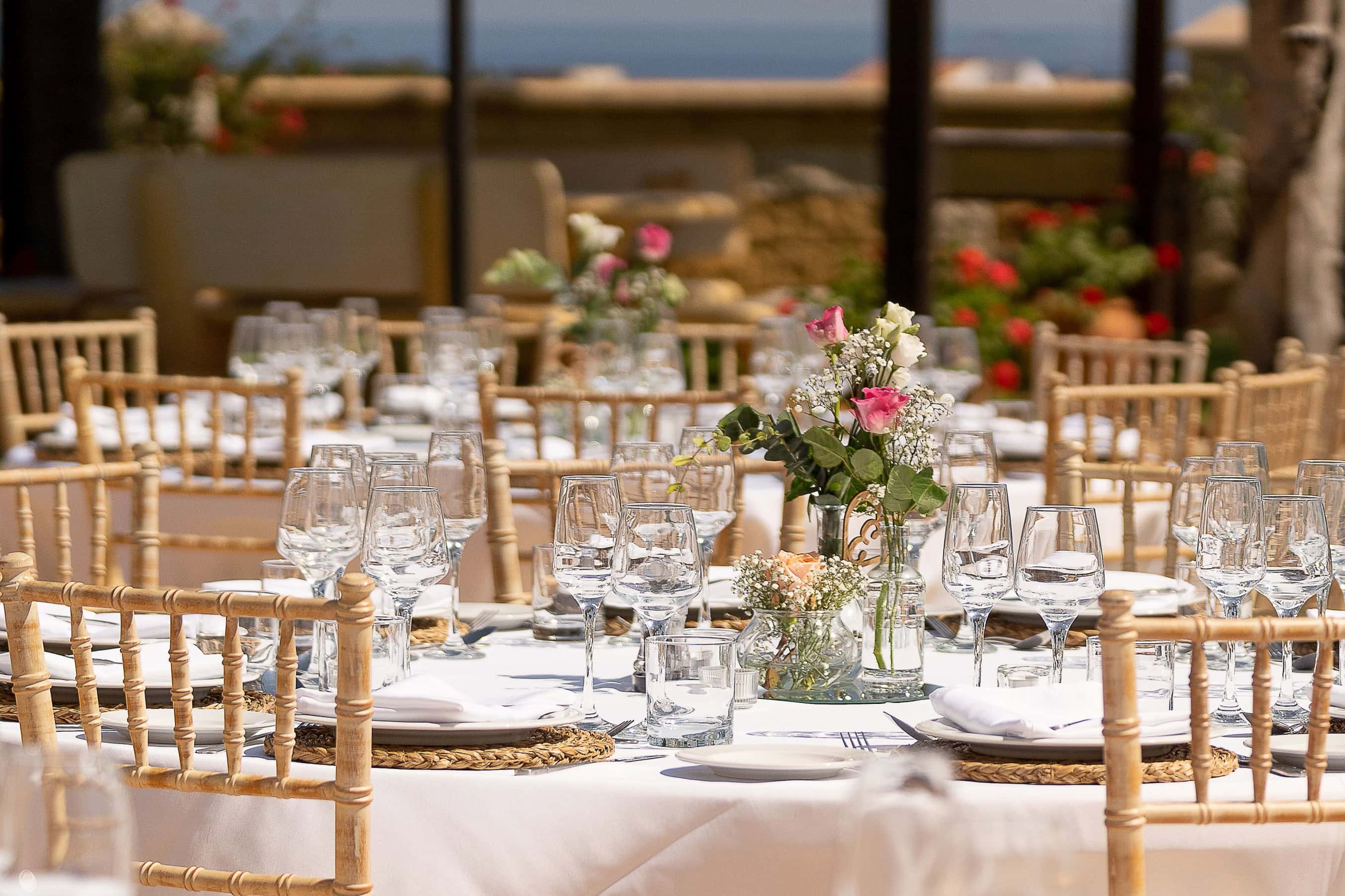 Luxury Hotel Event Styling – Elegant Table Setting with Sea View | Silverscreen Film & Photography Elegant outdoor event table setting with floral centrepieces and glassware at a luxury hotel venue overlooking the sea