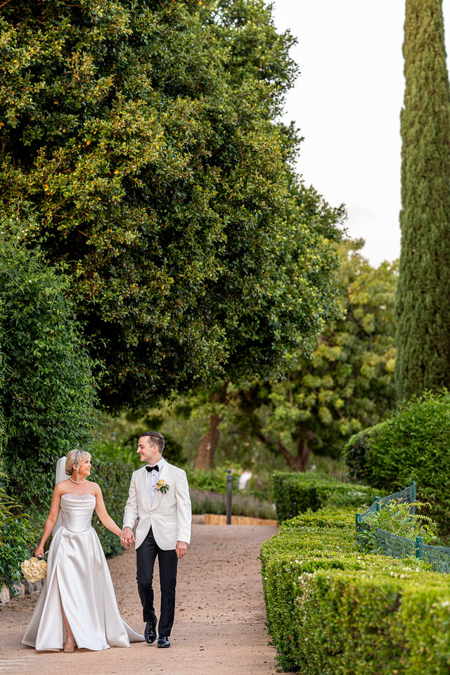 Bride and groom walking through wedding venue gardens during destination wedding