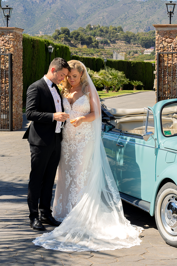 Bride and groom standing beside a classic Volkswagen Beetle at Cortijo Maria Luisa, Nerja, Spain. Photo by Dougie Farrelly, renowned Irish Professional Wedding Photographer, recommended for Irish Weddings in Spain. Silverscreen Film & Photography