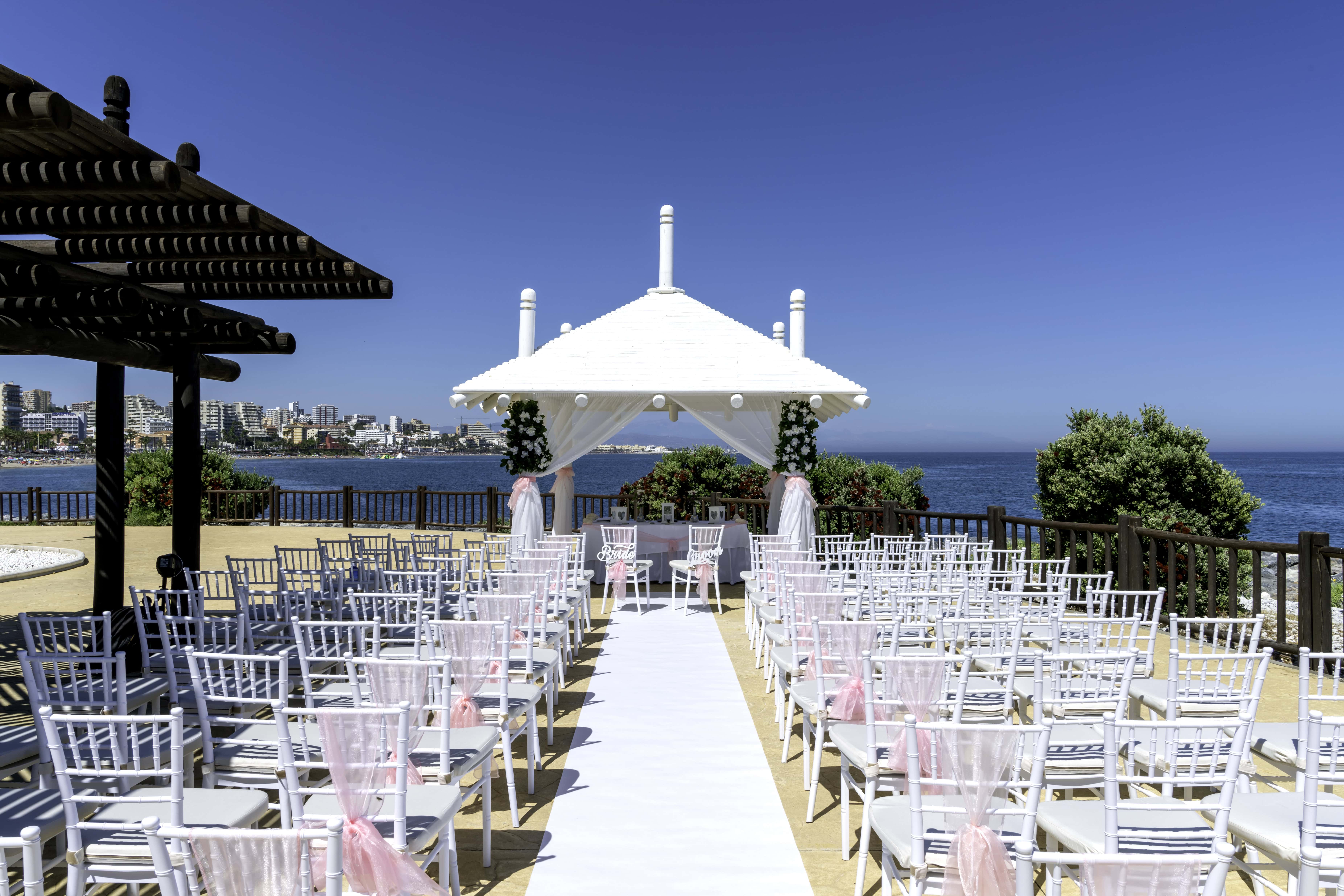 Sunset Beach Club Wedding Ceremony Setup – Benalmádena, Costa del Sol | Silverscreen Film & Photography Outdoor wedding ceremony setup at Sunset Beach Club Benalmádena with white aisle, chairs and sea view on the Costa del Sol