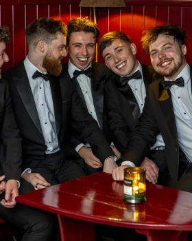 Groom and four groomsmen laughing together during a Ballymagarvey Village wedding