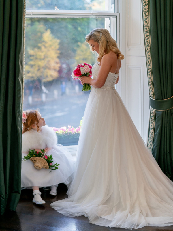 Bride by a window with a young wedding attendant at The Shelbourne Hotel in Dublin. © All Rights Reserved Dougie Farrelly Silverscreen.ie