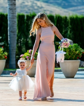 in a blush pink dress walking hand in hand with a young flower girl Bridesmaid at Rachel and George McMahon's wedding in Nerja, Spain.