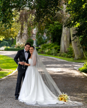 Bride and groom smiling with arms around each other holding champagne glasses at Ballymagarvey Village wedding in Ireland