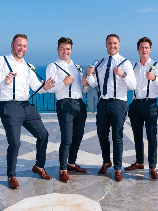 Groomsmen wearing suspenders posing together with a sea view during a wedding in Nerja, Spain.